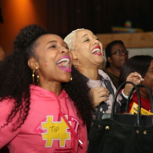Two audience members laughing, one in a CultureTags hoodie