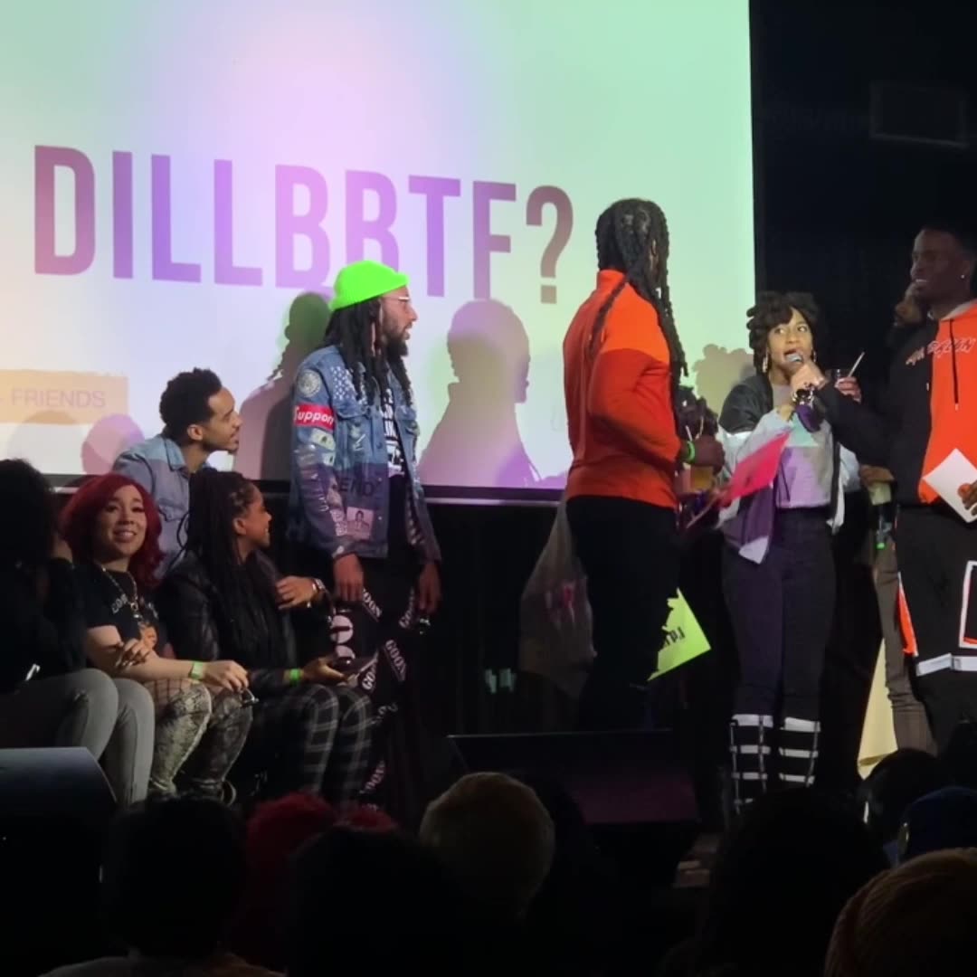 Players onstage under a big-screen prompt, DILLBRTF?