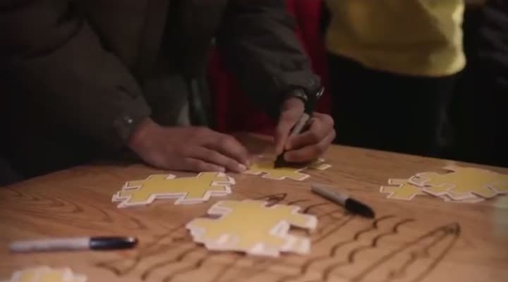 Hands working on yellow hashtag-shaped cutouts with Sharpies