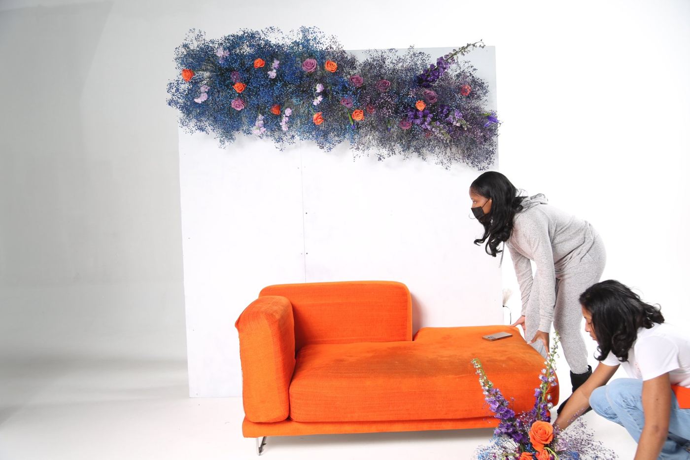 Aja placing the orange chaise beneath the floral installation during the Homegrown build