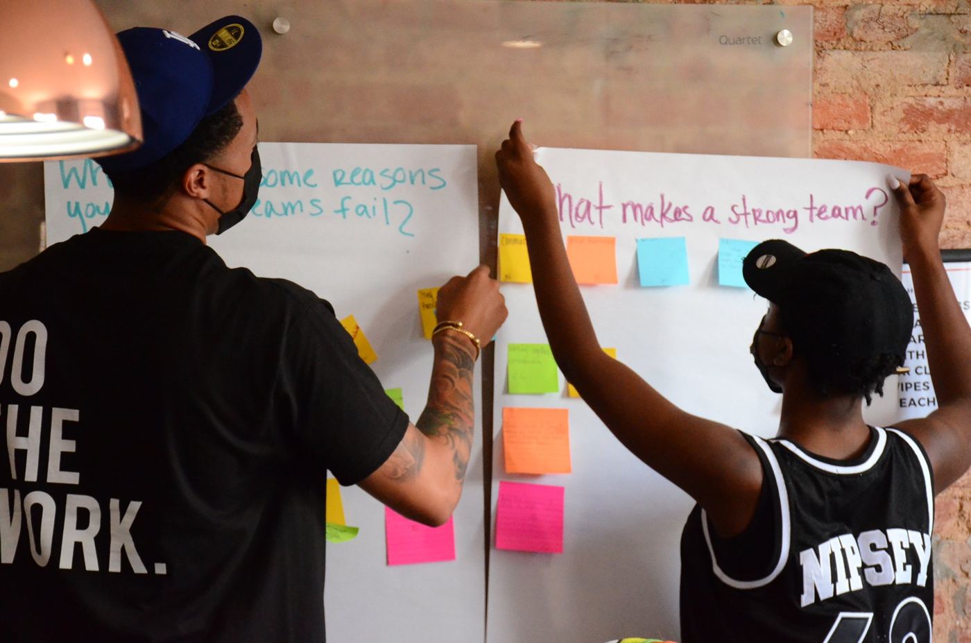 Crew members adding sticky notes to a “What makes a strong team?” board