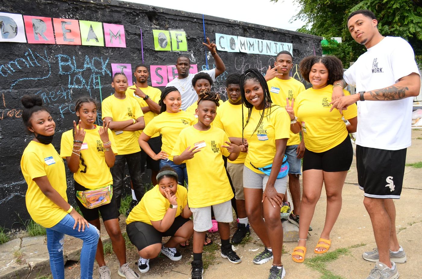 The DOTHEWORK crew in yellow at the “Dream of Community” wall, Soufside Market