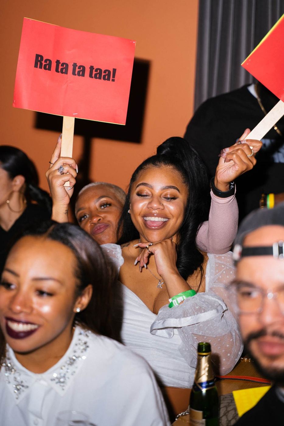 A guest mid-laugh, eyes closed, holding a sign