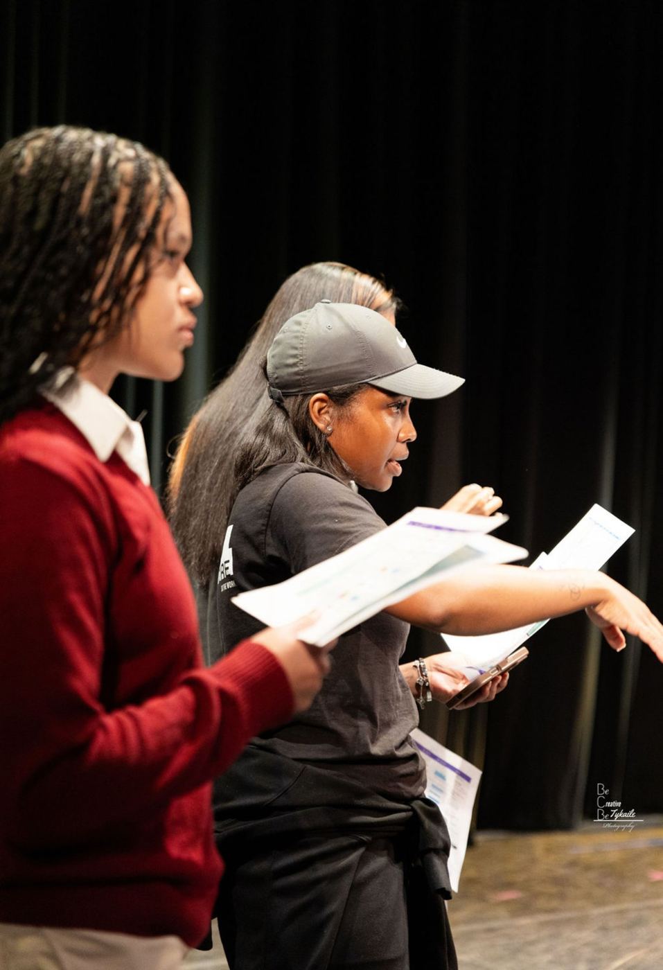 Aja directing young crew members with show paperwork on stage