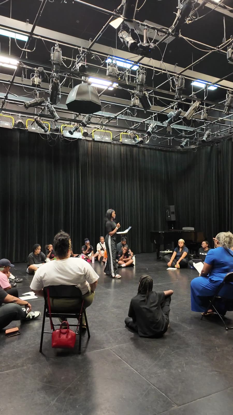 Rehearsal in the black box: the cast and youth crew seated in a circle
