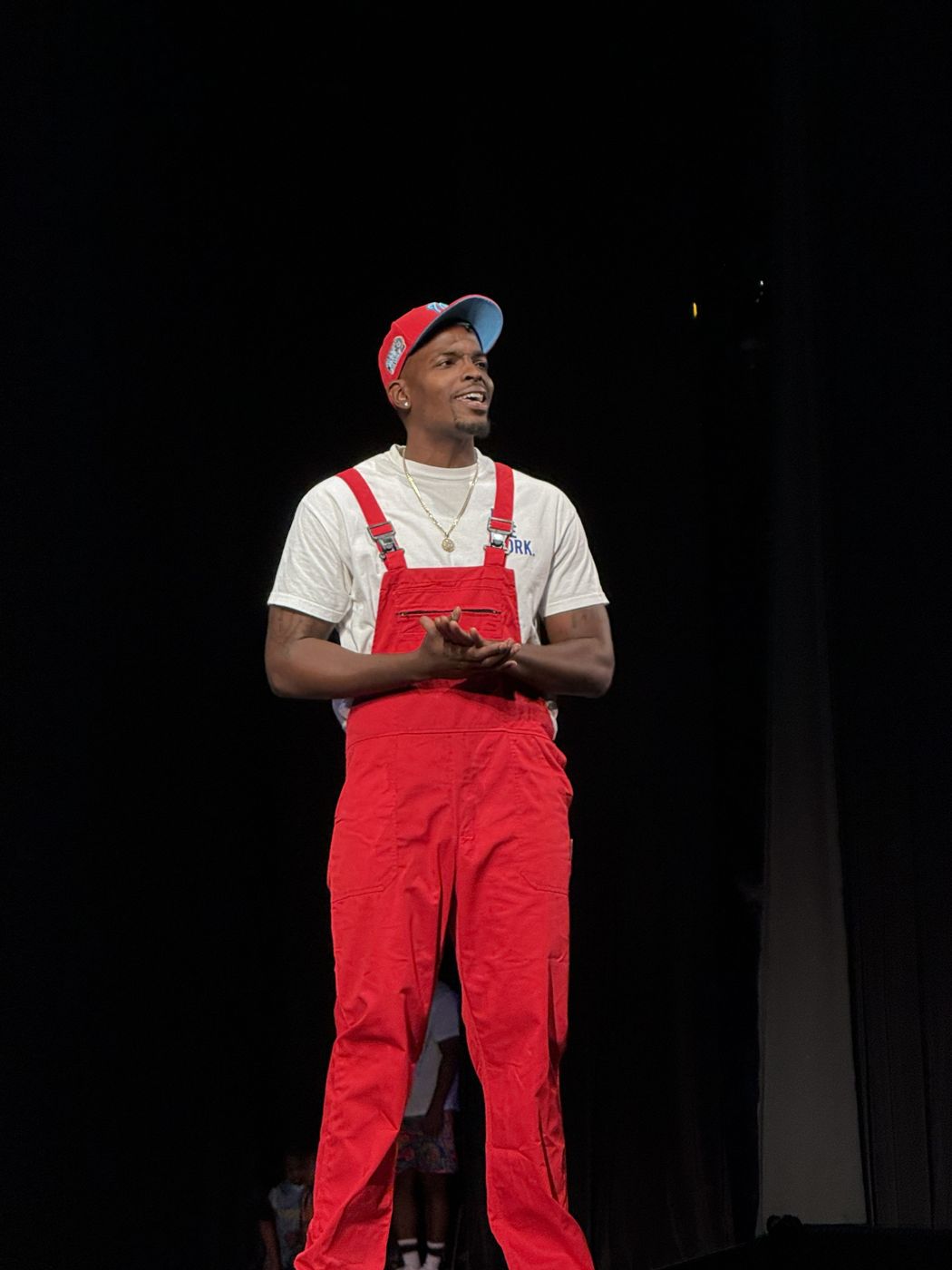 Mr. Prather onstage in his red overalls and cap, smiling at the audience