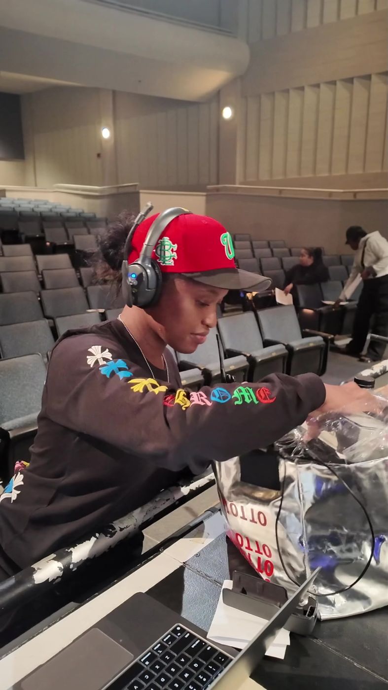 Aja on headset at the tech table in the empty house
