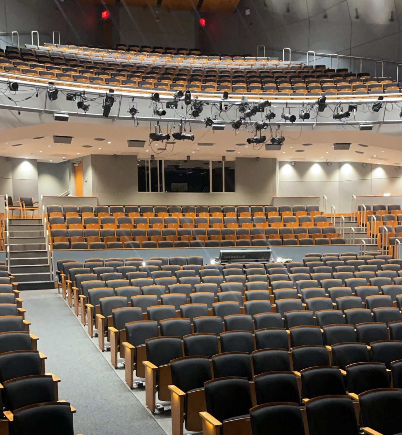 An empty theater house seen from the stage, with the lighting rail above